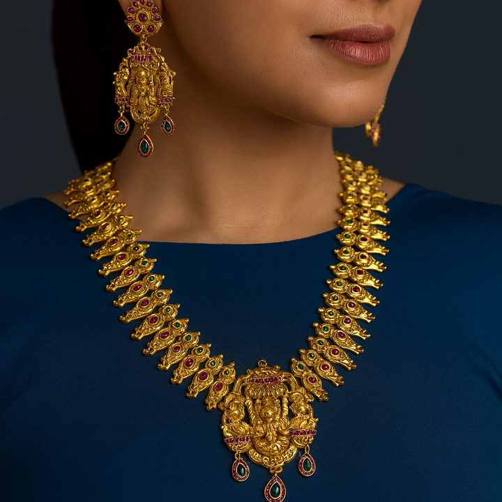 Woman wearing a gold necklace and earrings on a dark background